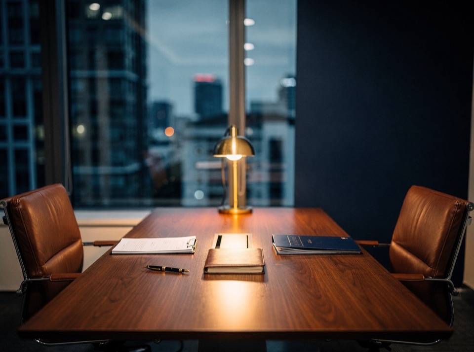 The firm’s meeting room at dusk, walnut table and leather chairs, ready