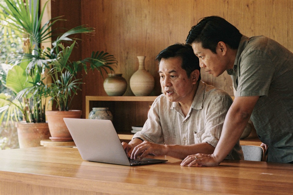 Hotel owner and marketing coordinator comparing a website page and local listing at a table