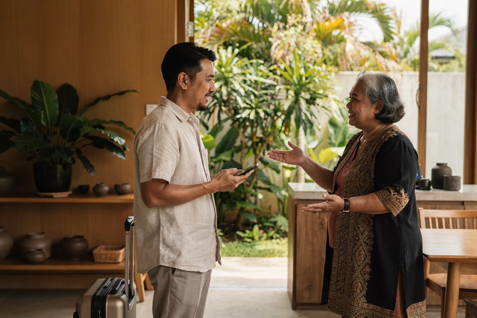 Arriving hotel guest checking information on a phone while a host offers help in the lobby